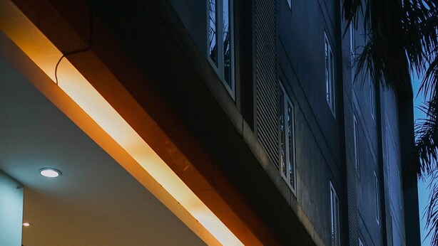 Un edificio con un espacio exterior techado, columnas y plantas en macetas.
