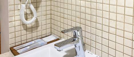 A bathroom with a white sink, a chrome faucet, a hairdryer, and a mirror.