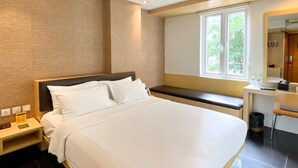 Una habitación de hotel moderna con una cama grande, un escritorio y una ventana con vistas a zonas verdes.