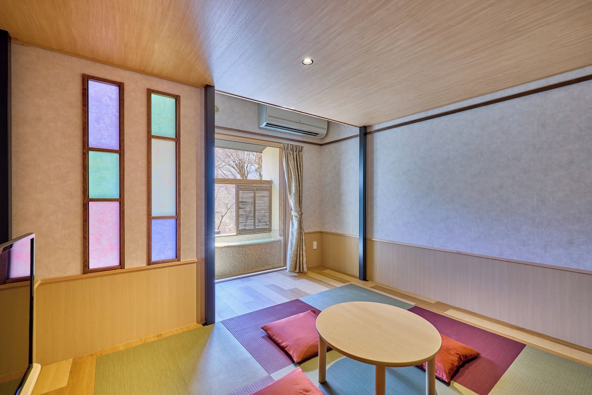 A room with tatami mats, a tatami mat table, and a sliding door leading to a balcony.