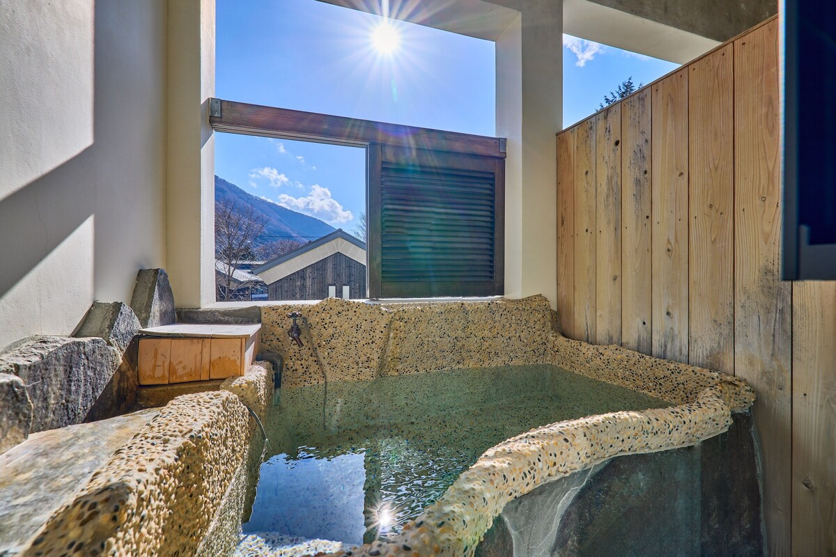 A hot spring bath area with a view of mountains through a window.