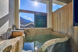 Zona de baño termal con vistas a las montañas a través de una ventana.