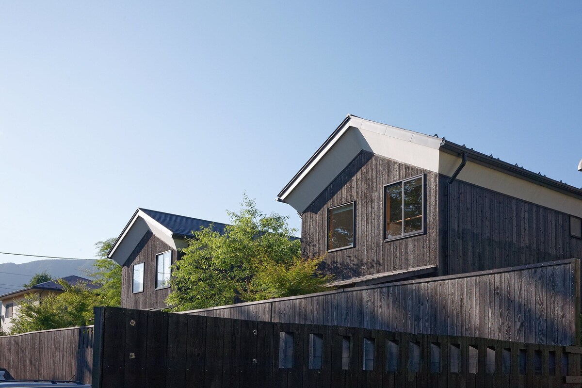 A modern two-story house with a wooden exterior and a sloped roof.