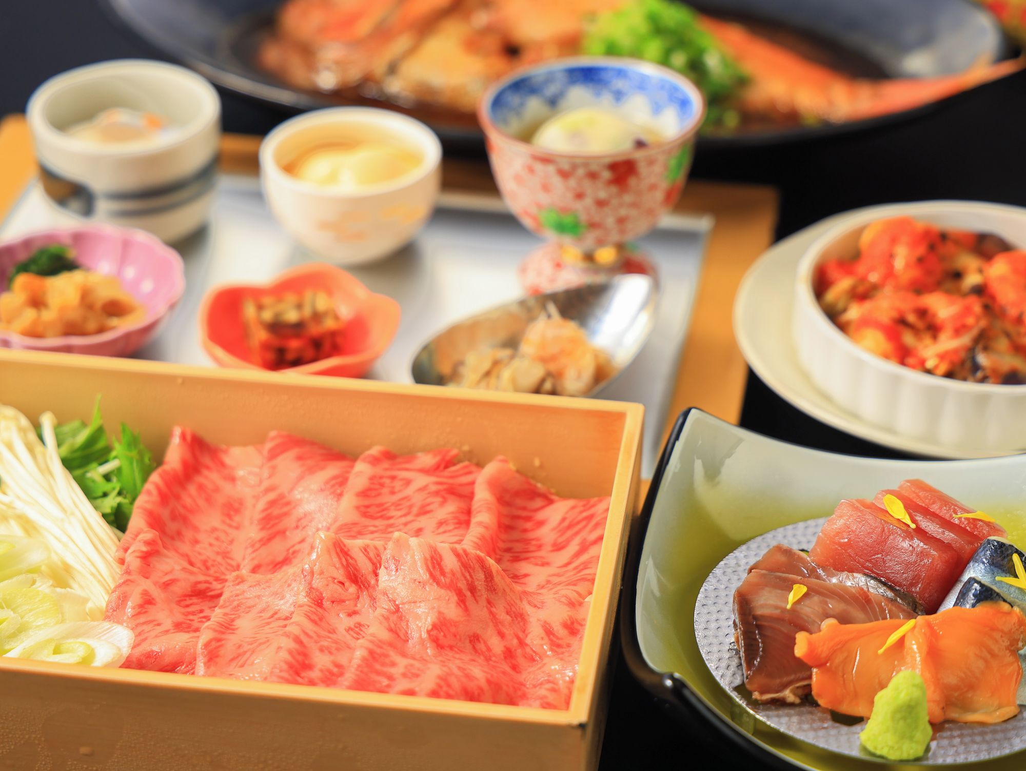 A variety of Japanese dishes including sashimi and sushi, served on a table with multiple bowls and plates.