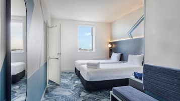 Una habitación de hotel con cama, mesita de noche y espejo.