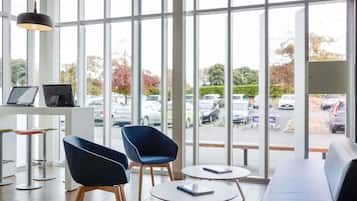 Un interior moderno con ventanas amplias, una zona de estar y una mesa con portátiles.