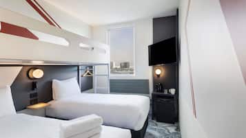 A hotel room with two beds, a TV, a desk with a coffee maker, and a city view.