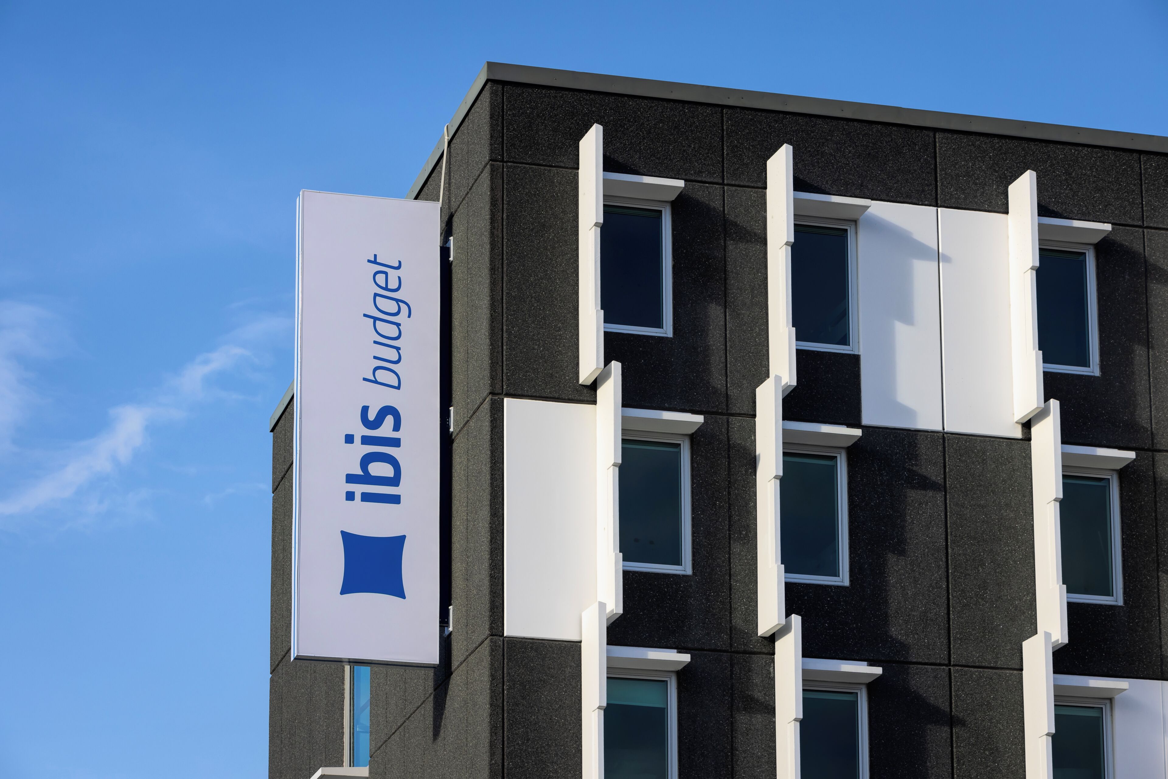 Un bâtiment avec une enseigne indiquant « ibis budget » et de nombreuses fenêtres.