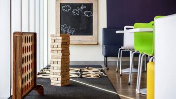 A room with a wooden block tower, a chalkboard with drawings, and colorful chairs.