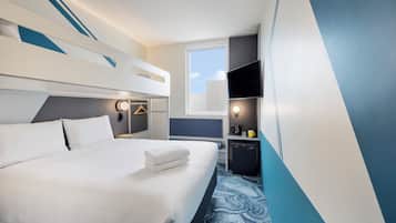 A hotel room with a bed, bedside table, TV, and a small kitchenette.