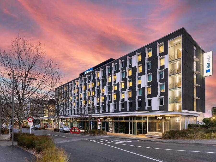 A modern hotel with a black and white facade, multiple windows, and a visible entrance.