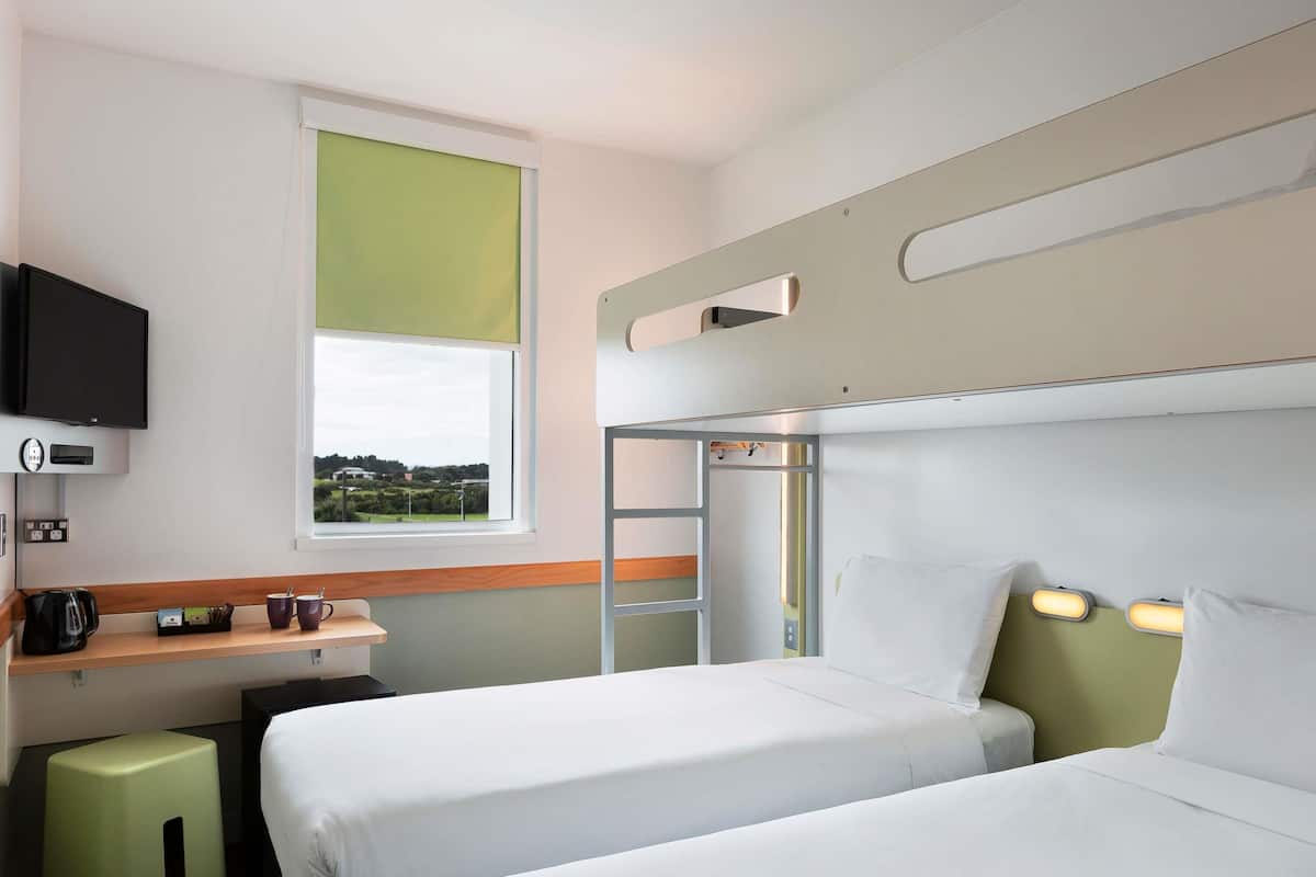 Une chambre d’hôtel avec deux lits, un bureau, une télévision et une fenêtre donnant sur un paysage agréable.