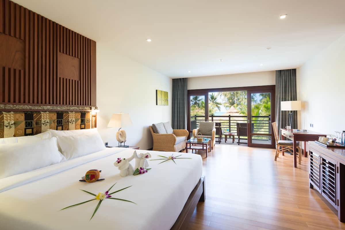 Een hotelkamer met een groot bed, een zithoek en uitzicht op het landschap.