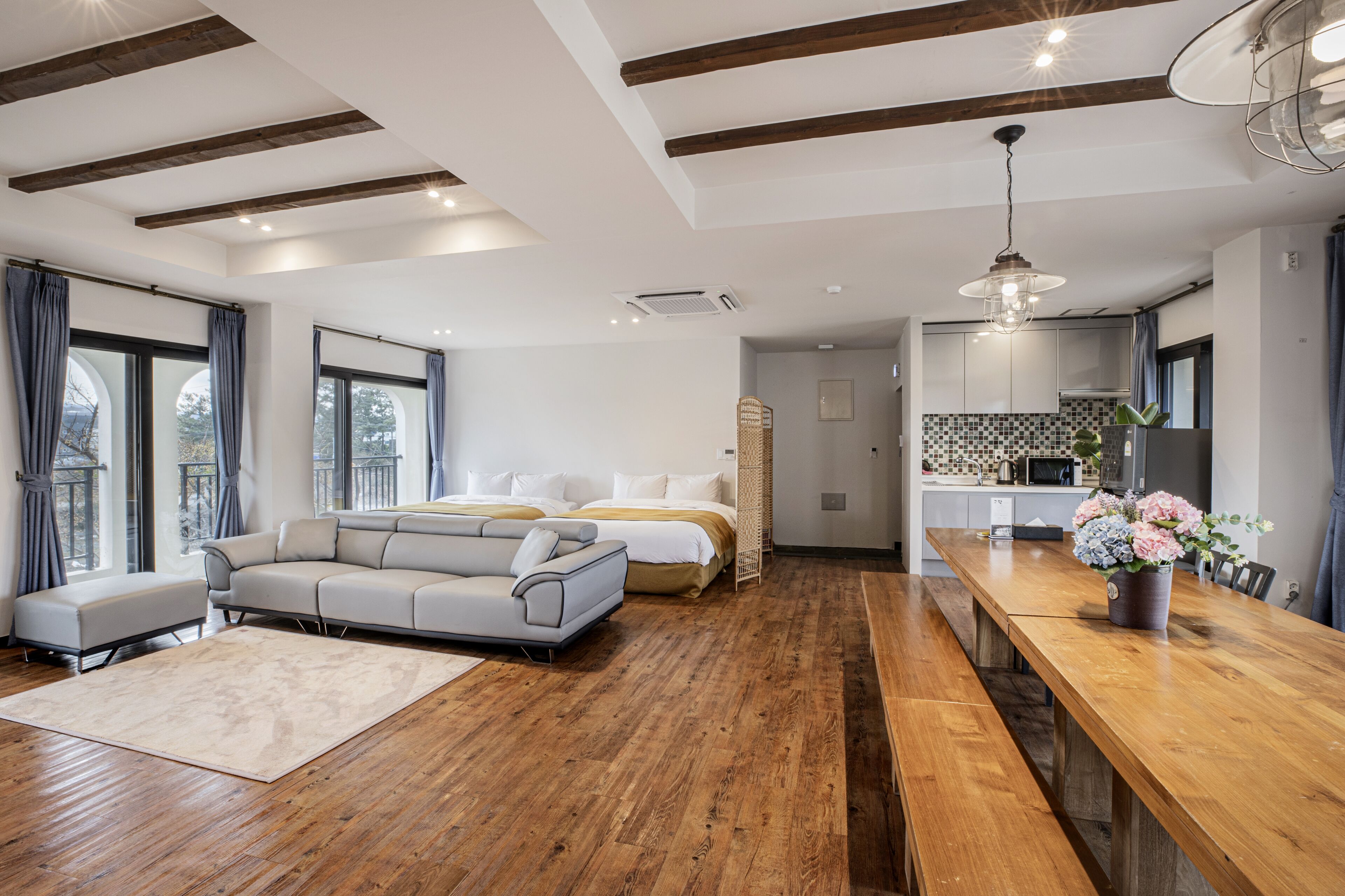 Un dormitorio moderno con una cama grande, un sofá y una zona de comedor con una mesa de madera y un banco.