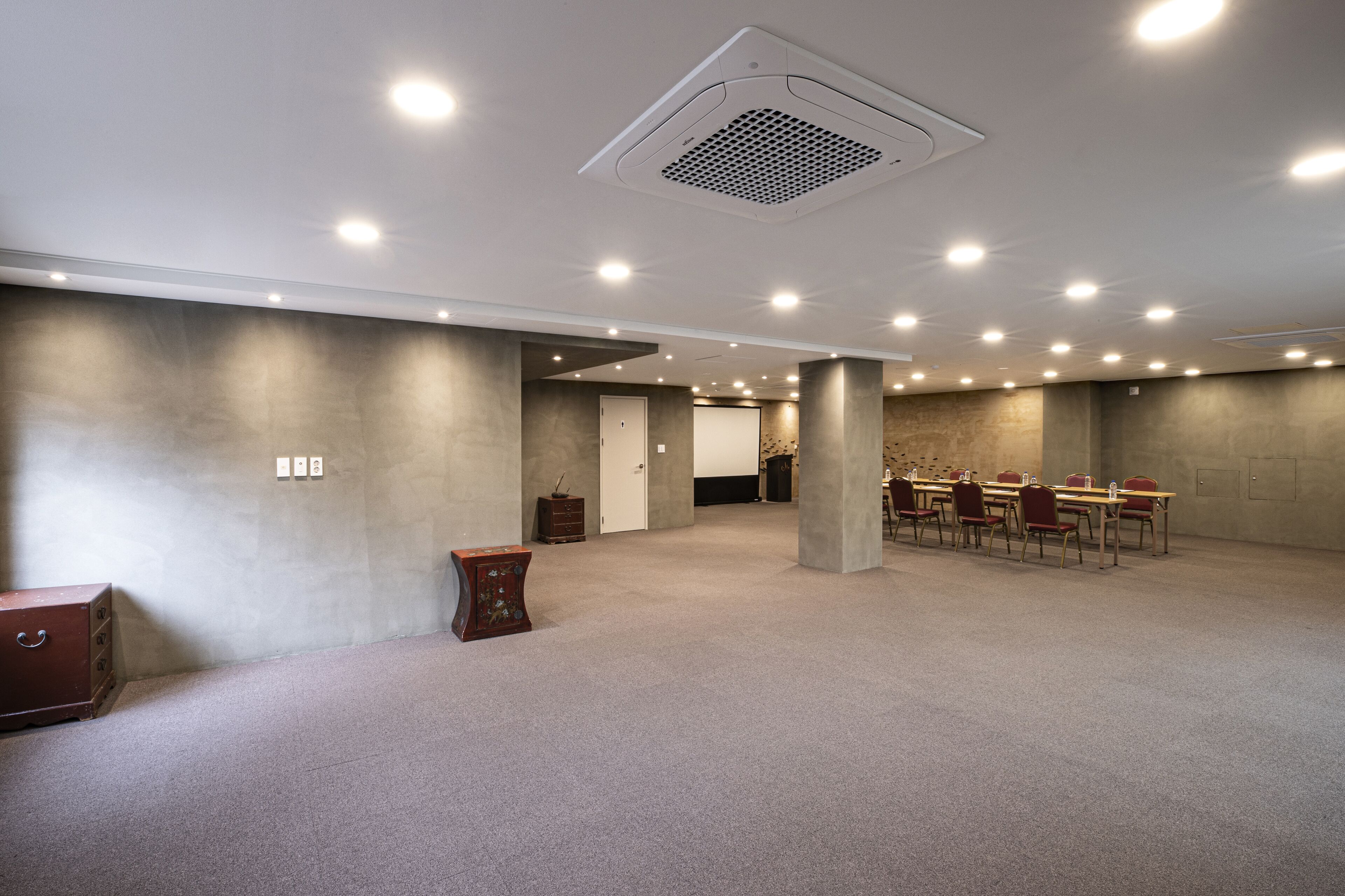 Une salle de conférence spacieuse, dotée d’un haut plafond, d’un éclairage encastré et d’une table centrale entourée de chaises.