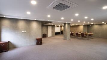 Une salle de conférence spacieuse, dotée d’un haut plafond, d’un éclairage encastré et d’une table centrale entourée de chaises.