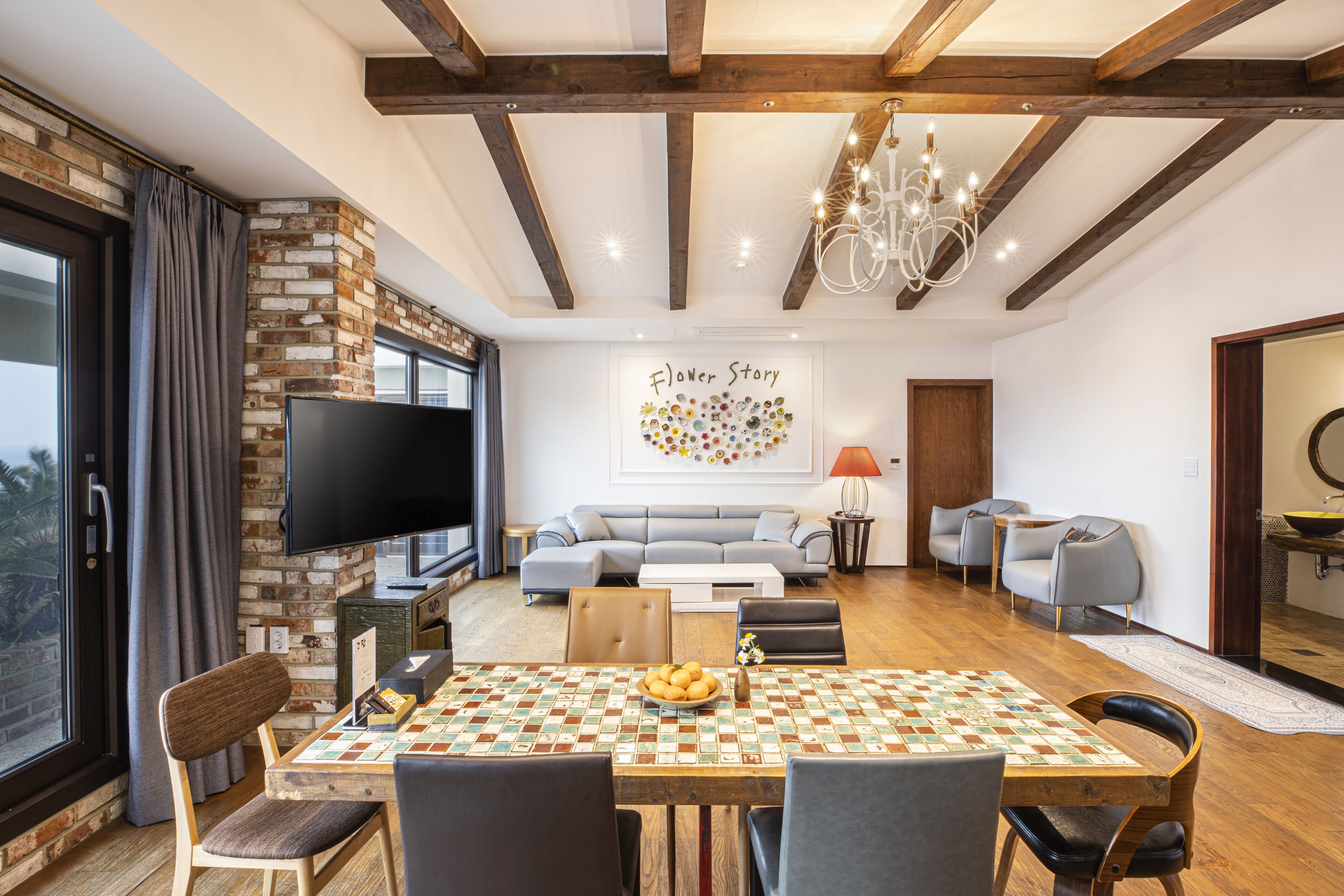 Una sala de estar moderna con techo de madera, televisor, sofá y una mesa de comedor con sillas.