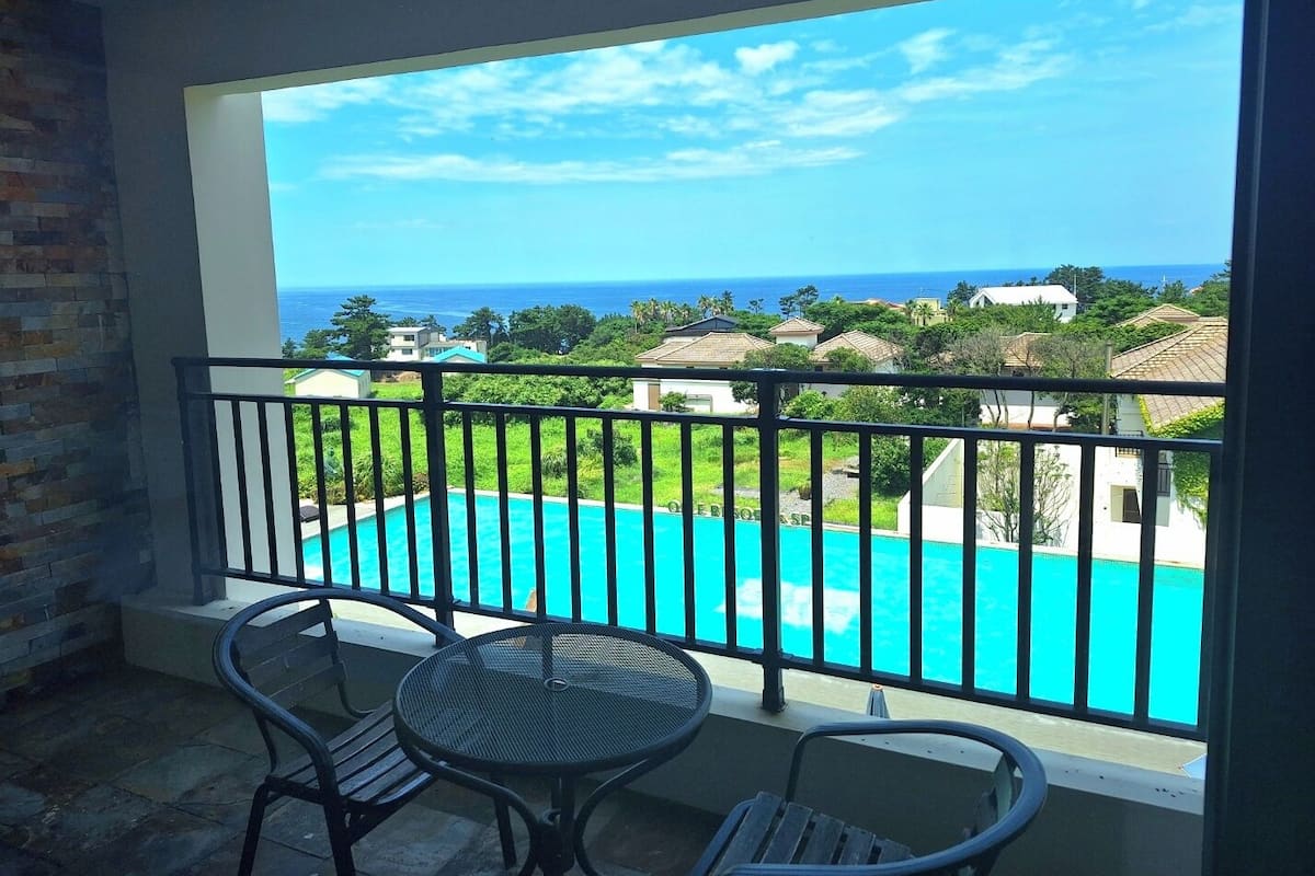 A balcony with a view of a turquoise pool and ocean.
