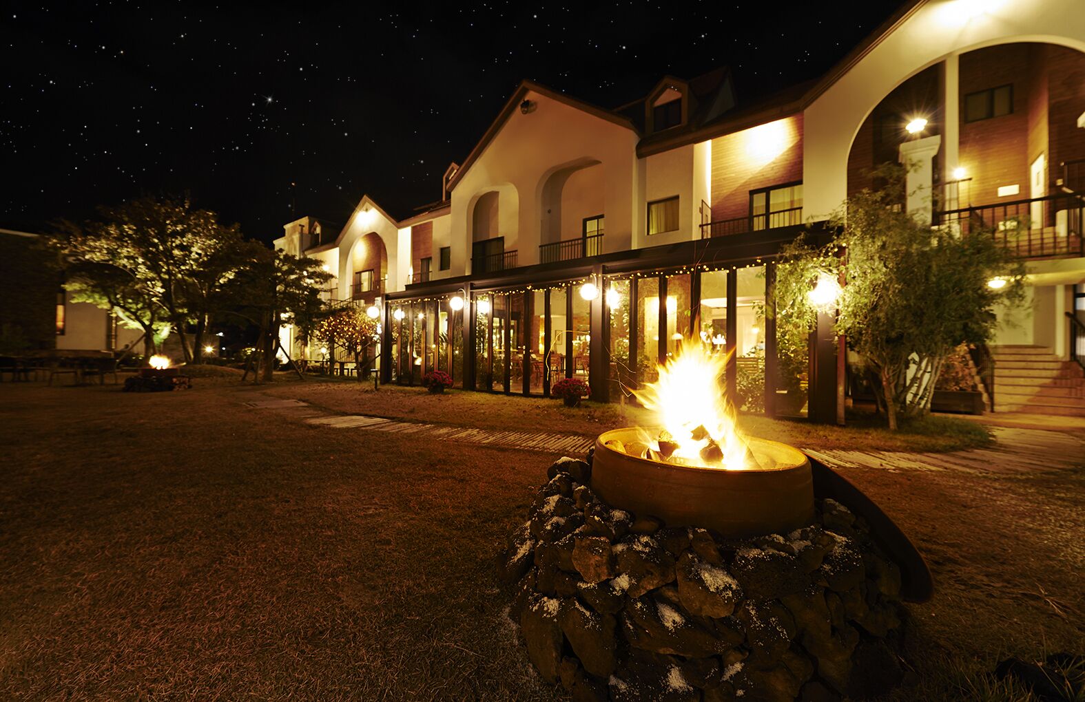 A hotel with a fire pit in the courtyard, outdoor seating, and a covered patio area.