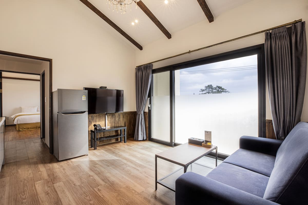 A modern living room with a sofa, a coffee table, a TV, and a refrigerator.