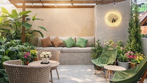 A covered patio area with wicker furniture, a seating bench, and potted plants. - Chiang Mai Waroros Boutique Hotel (Chiang Mai)