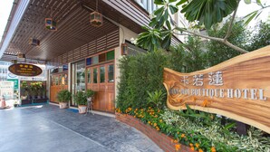 A hotel entrance with a wooden sign, potted plants, and a tiled walkway. - Chiang Mai Waroros Boutique Hotel (Chiang Mai)