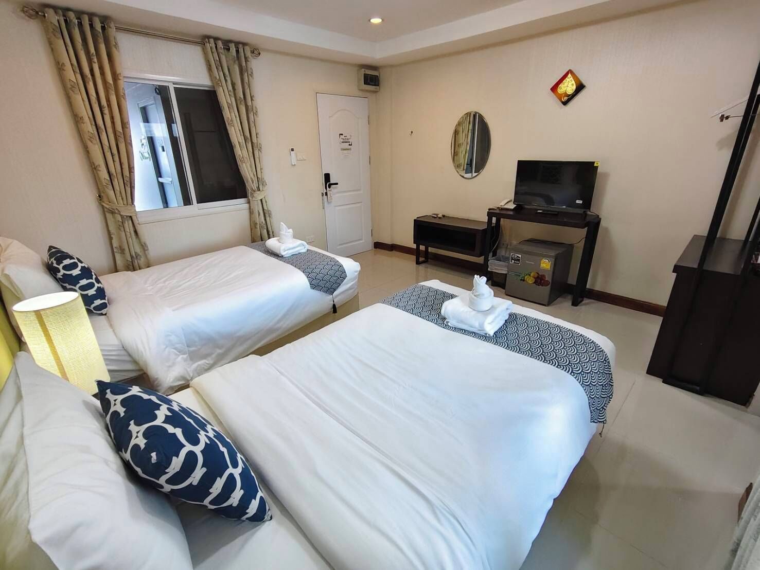 Une chambre d’hôtel avec deux lits, une télévision, un minibar et une porte.