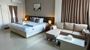 A hotel room with a bed, a sofa, a coffee table, and a wall-mounted air conditioner. - Chiang Mai Waroros Boutique Hotel (Chiang Mai)
