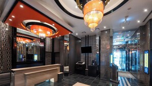 A modern lobby with a reception desk, a large chandelier, and a patterned floor. - APA Hotel Higashi Shinjuku Kabukicho (Tokyo)