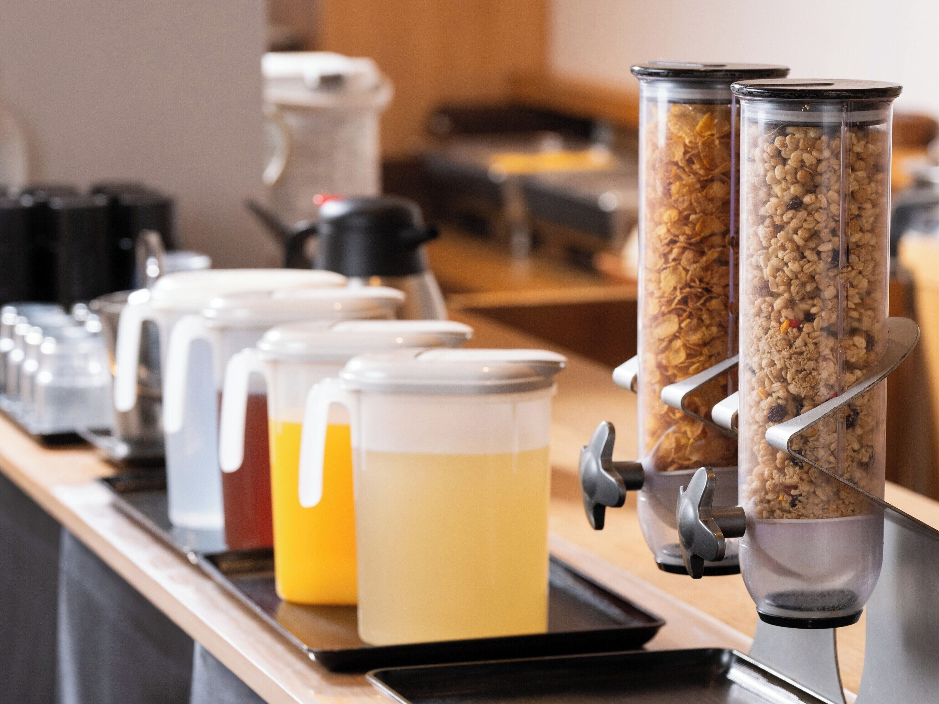 A breakfast bar with various containers of food and beverages, including cereal and juices.