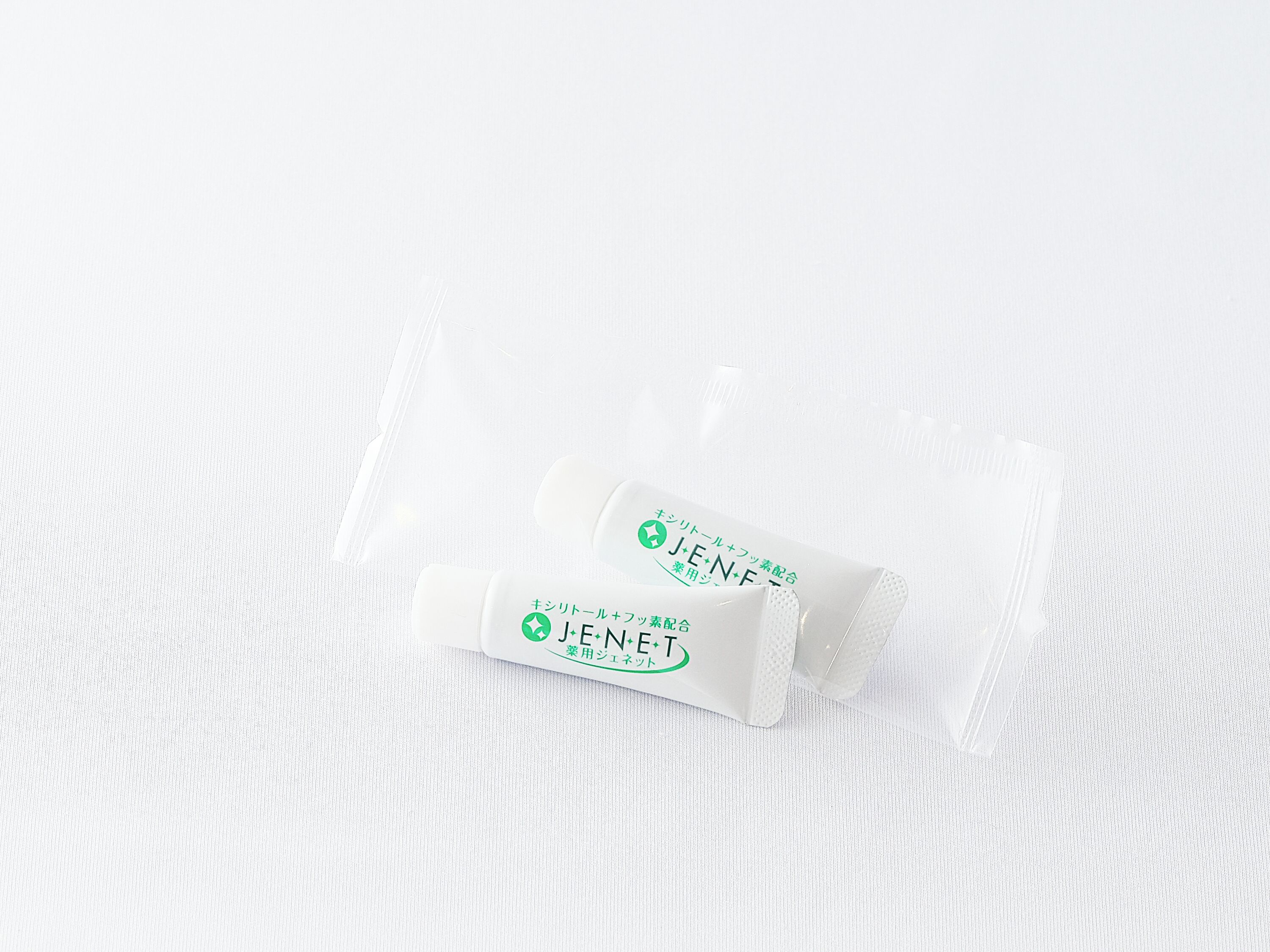 Two white sachets with green and black text on a white textured background.