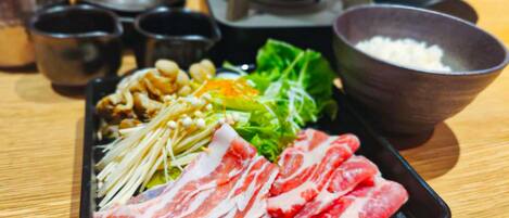 A tray with various food items including sliced meat, vegetables, and mushrooms.