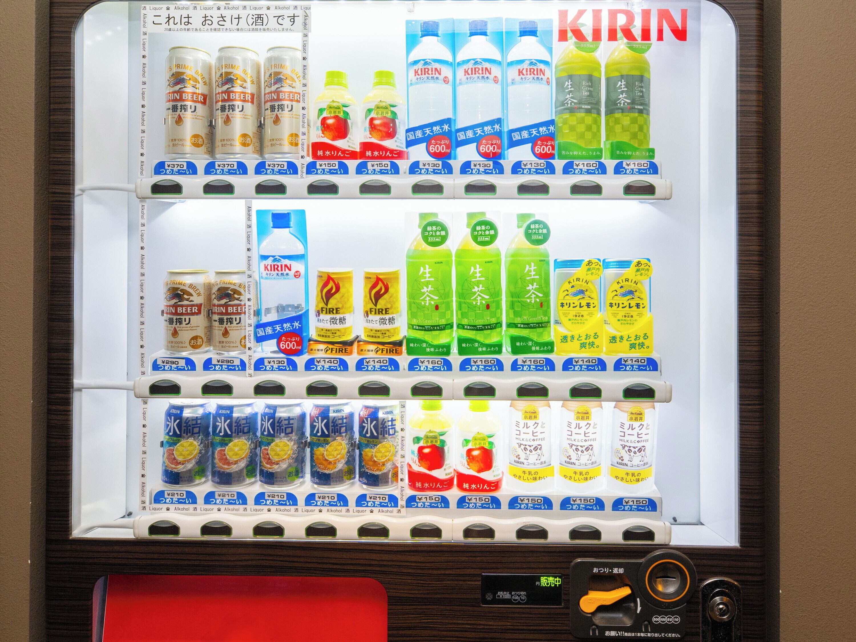 Een automaat met diverse drankjes, waaronder Kirin bier, Kirin thee en andere opties.