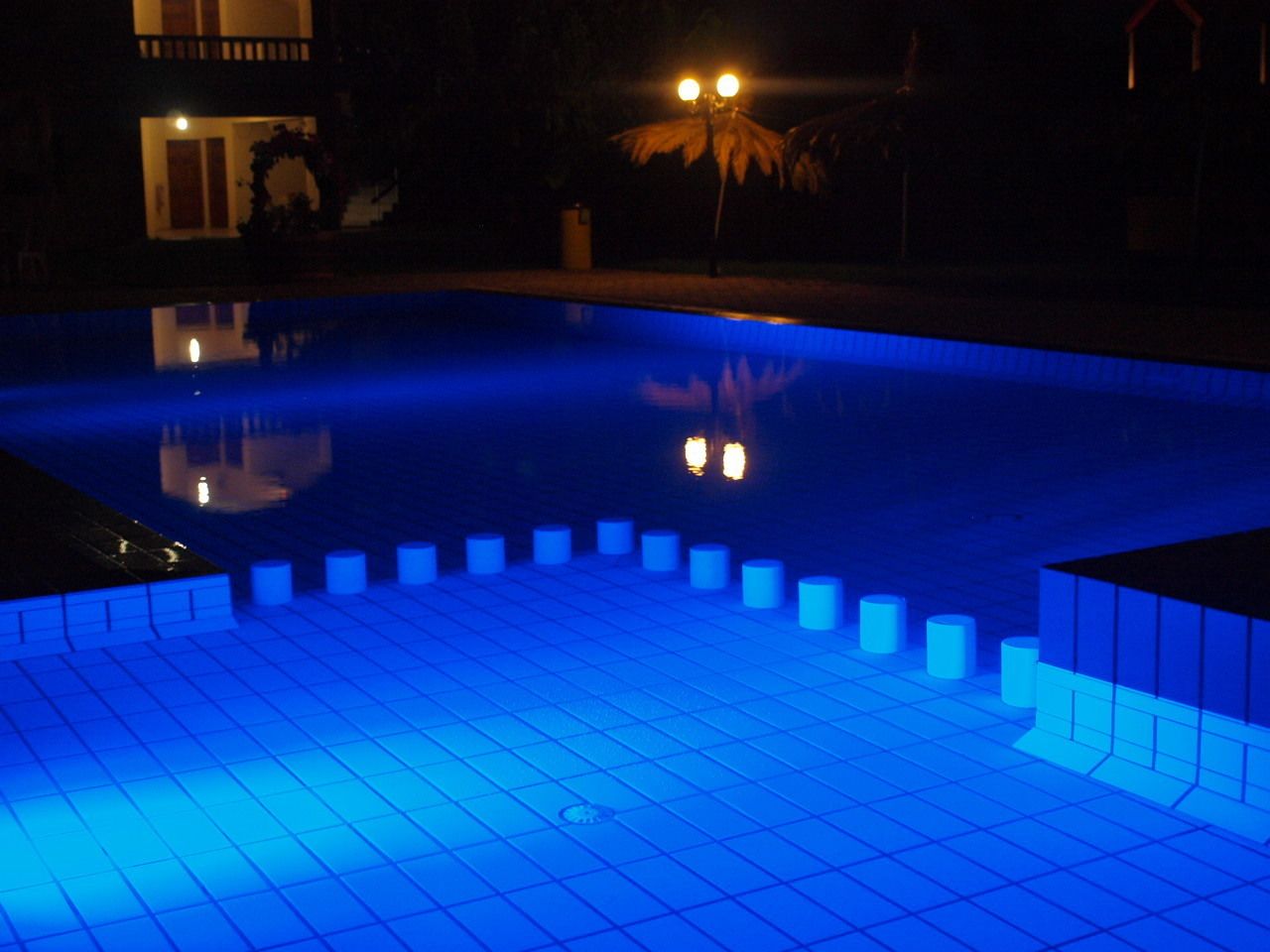 A nighttime view of a swimming pool with illuminated steps and a reflection of lights.