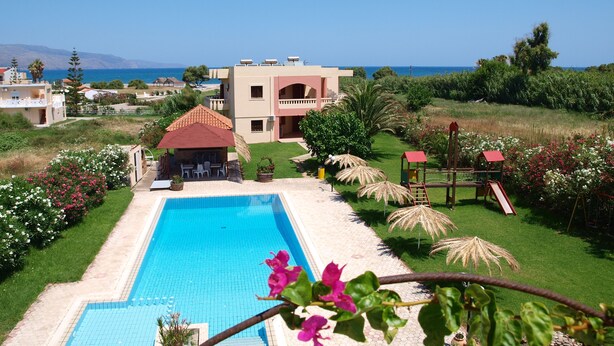 Una piscina con zona de patio, rodeada de exuberante vegetación y vista al mar.