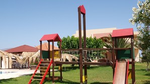 Un parque infantil con una estructura de escalada, toboganes y un puente colgante.