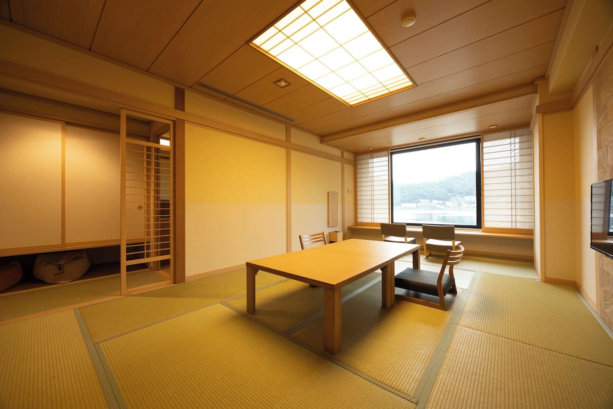 Une pièce de style japonais traditionnel, avec un sol recouvert de tatamis, une table basse et des portes coulissantes.