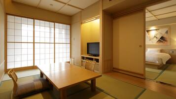 Quarto japonês tradicional com tatames, uma mesa baixa, televisão e cama com futon.