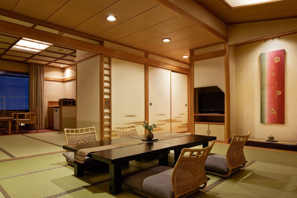 Une pièce de style japonais traditionnel, avec un sol recouvert de tatamis, une table basse et des paravents en papier de riz (shoji).