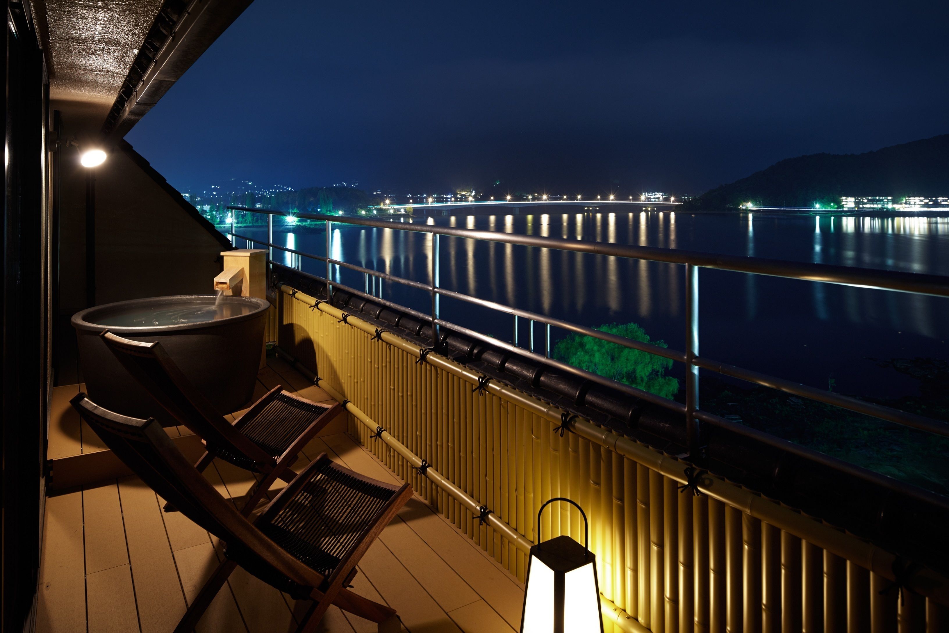 A balcony with a hot tub, chairs, and a lantern.