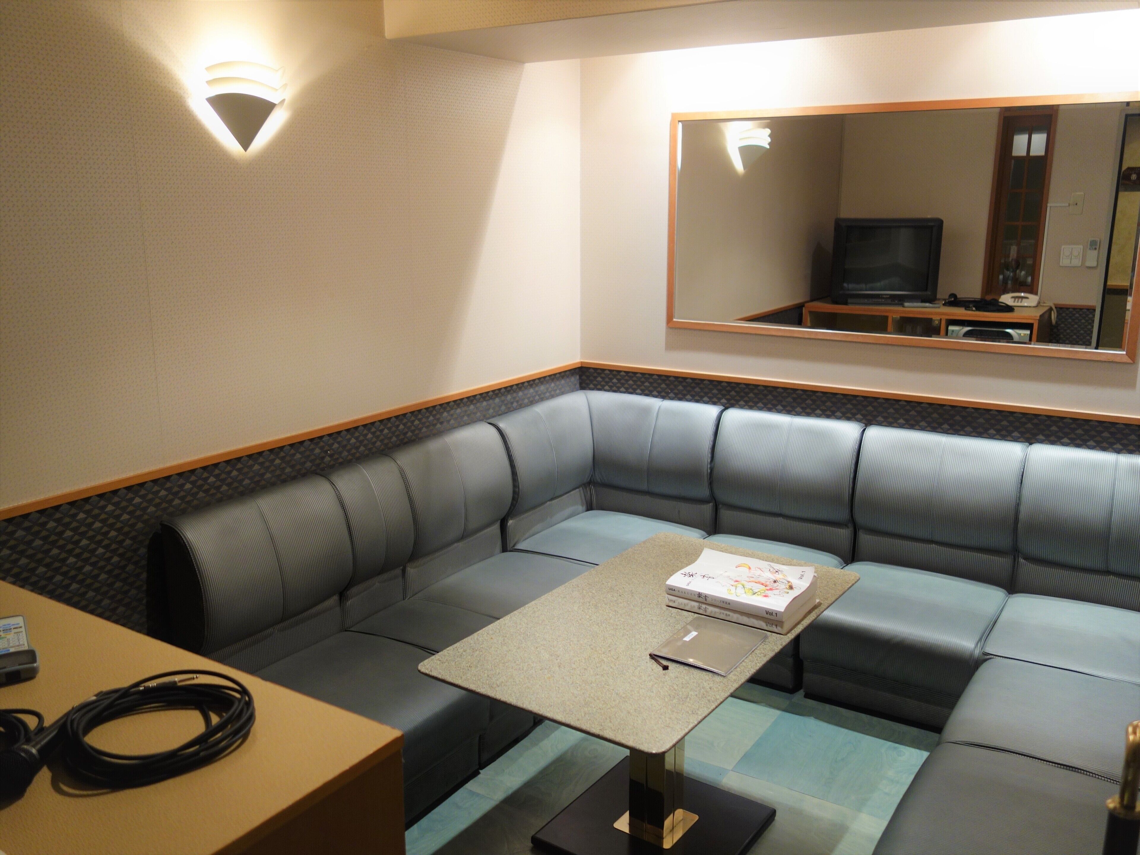 A modern hotel room with a sectional sofa, a small table, and a TV.