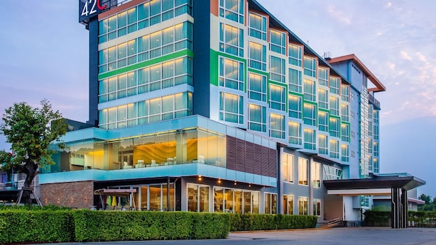 A multi-story hotel with a modern design, featuring a prominent entrance with glass doors and a covered outdoor seating area.