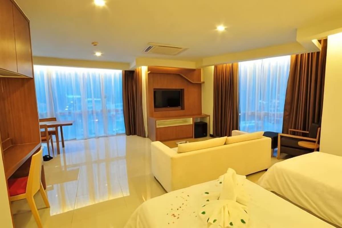 Habitación de hotel con balcón, televisor, sofá y cama.