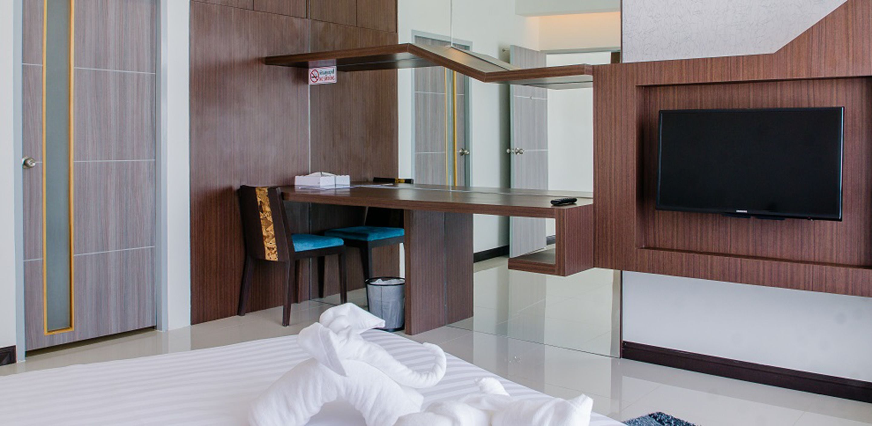 Una habitación de hotel moderna con una cama, un escritorio con silla, un televisor y un bote de basura.