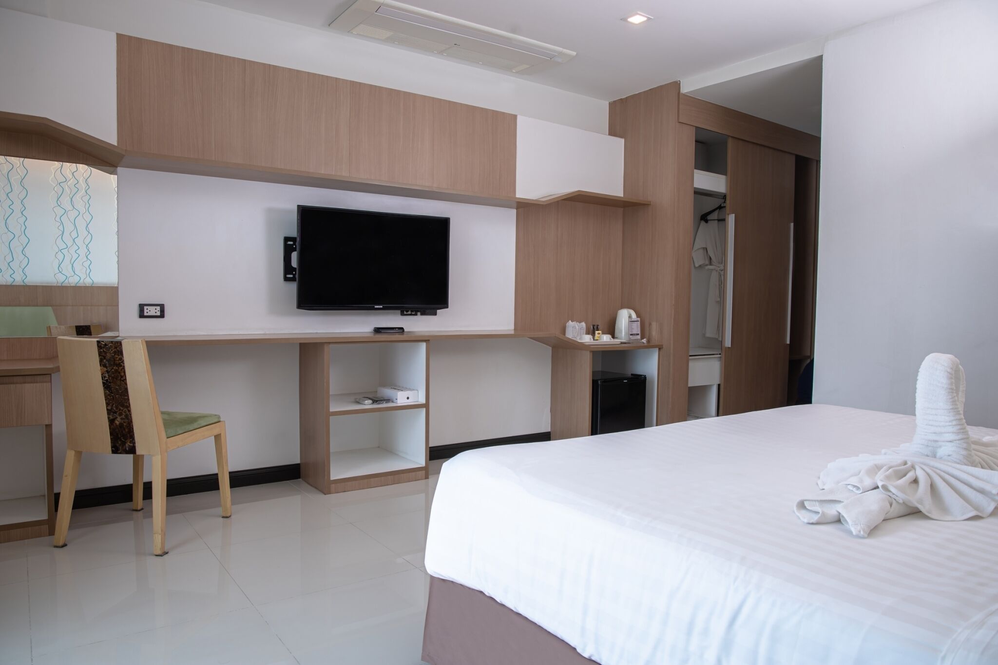 Ein Hotelzimmer mit Bett, Schreibtisch mit Stuhl, Fernseher, Kleiderschrank und Bad.