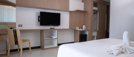 Ein Hotelzimmer mit Bett, Schreibtisch mit Stuhl, Fernseher, Kleiderschrank und Bad.