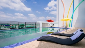 A rooftop pool with lounge chairs, a table, and an umbrella.