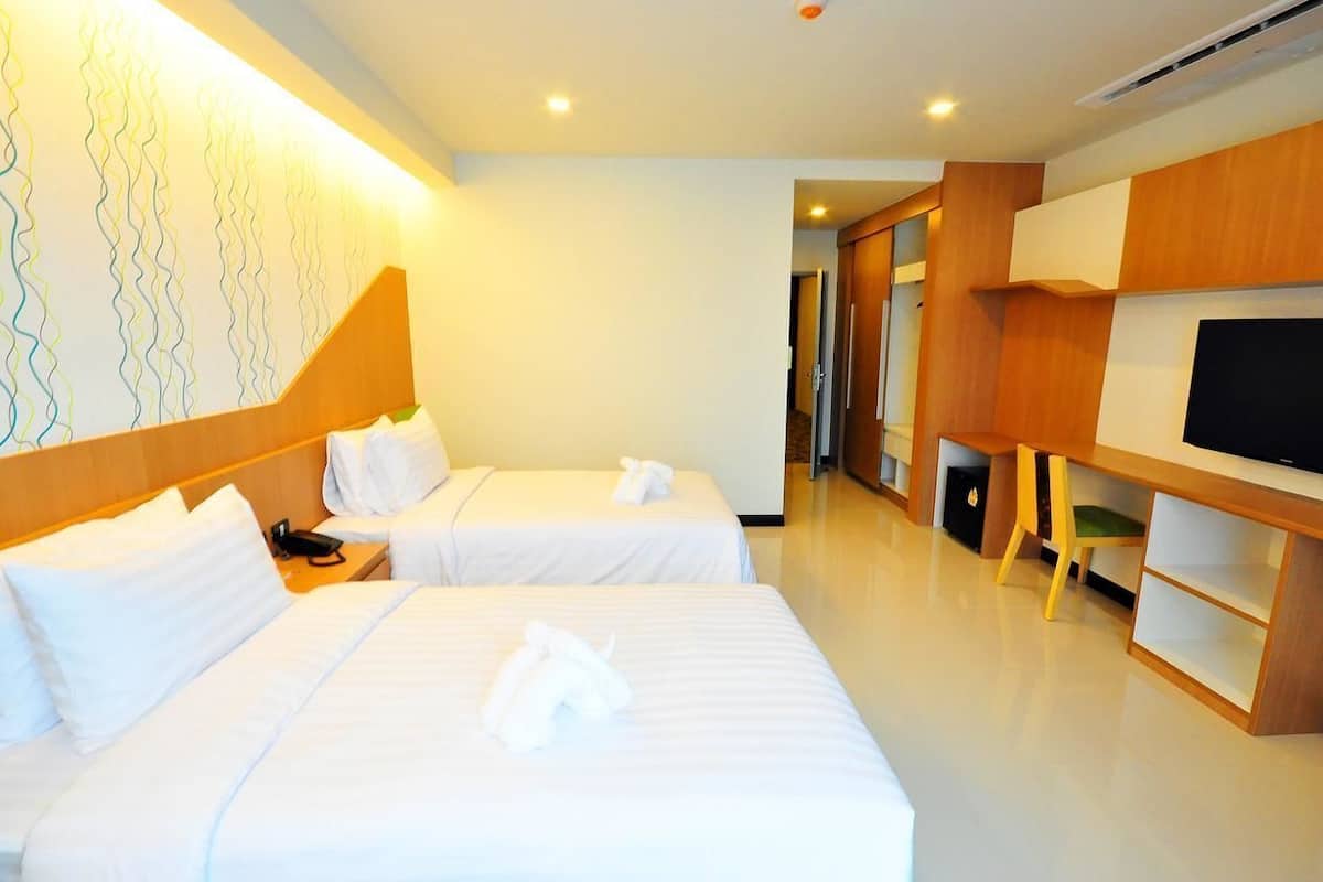 A hotel room with two beds, a TV, and a desk.