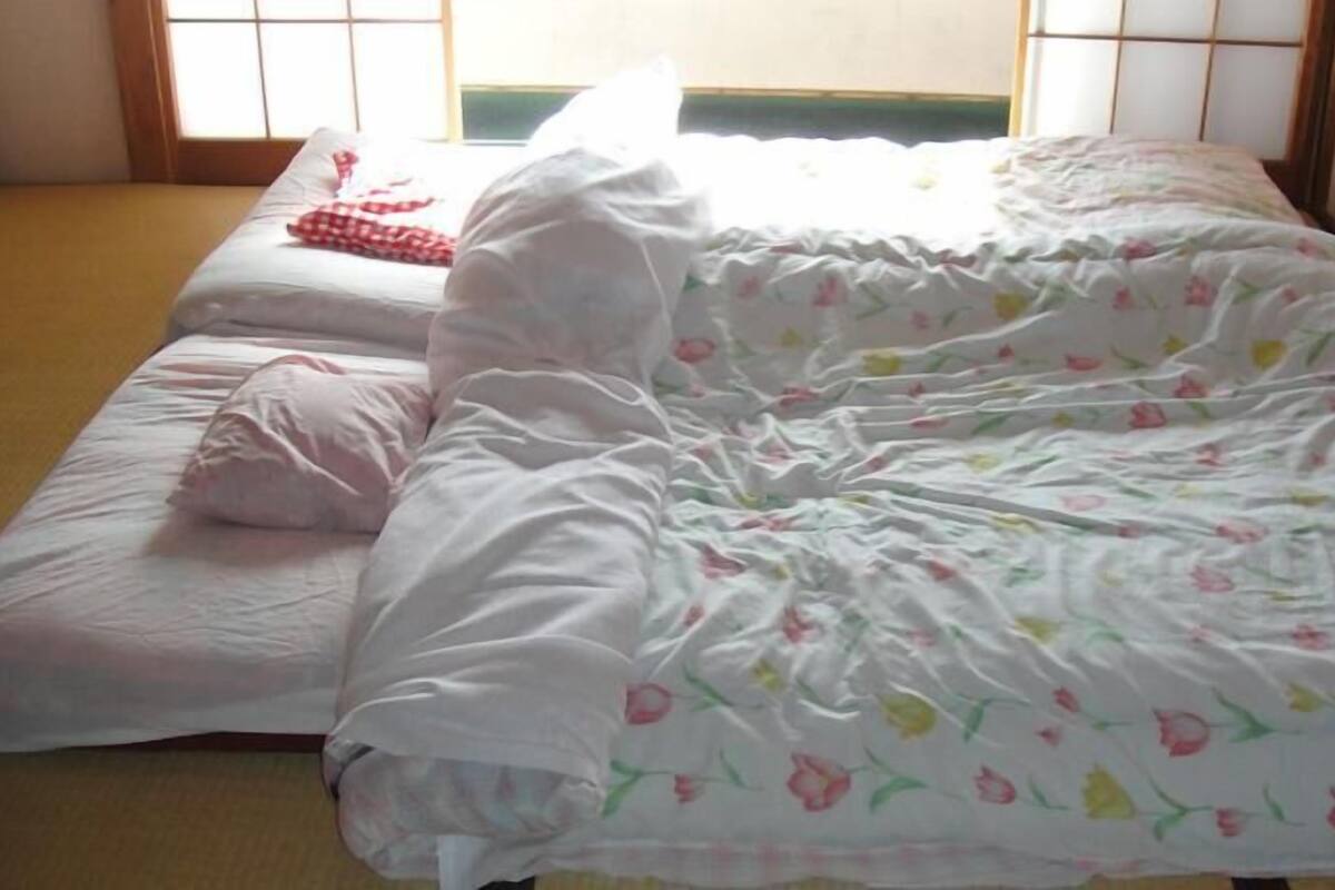 A room with two beds, one with a floral bedspread and the other with a plain white one.