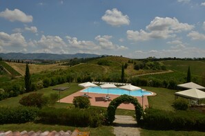 A pool area with umbrellas, surrounded by lush greenery and hills in the background. - Agriturismo Musignano (Cerreto Guidi)